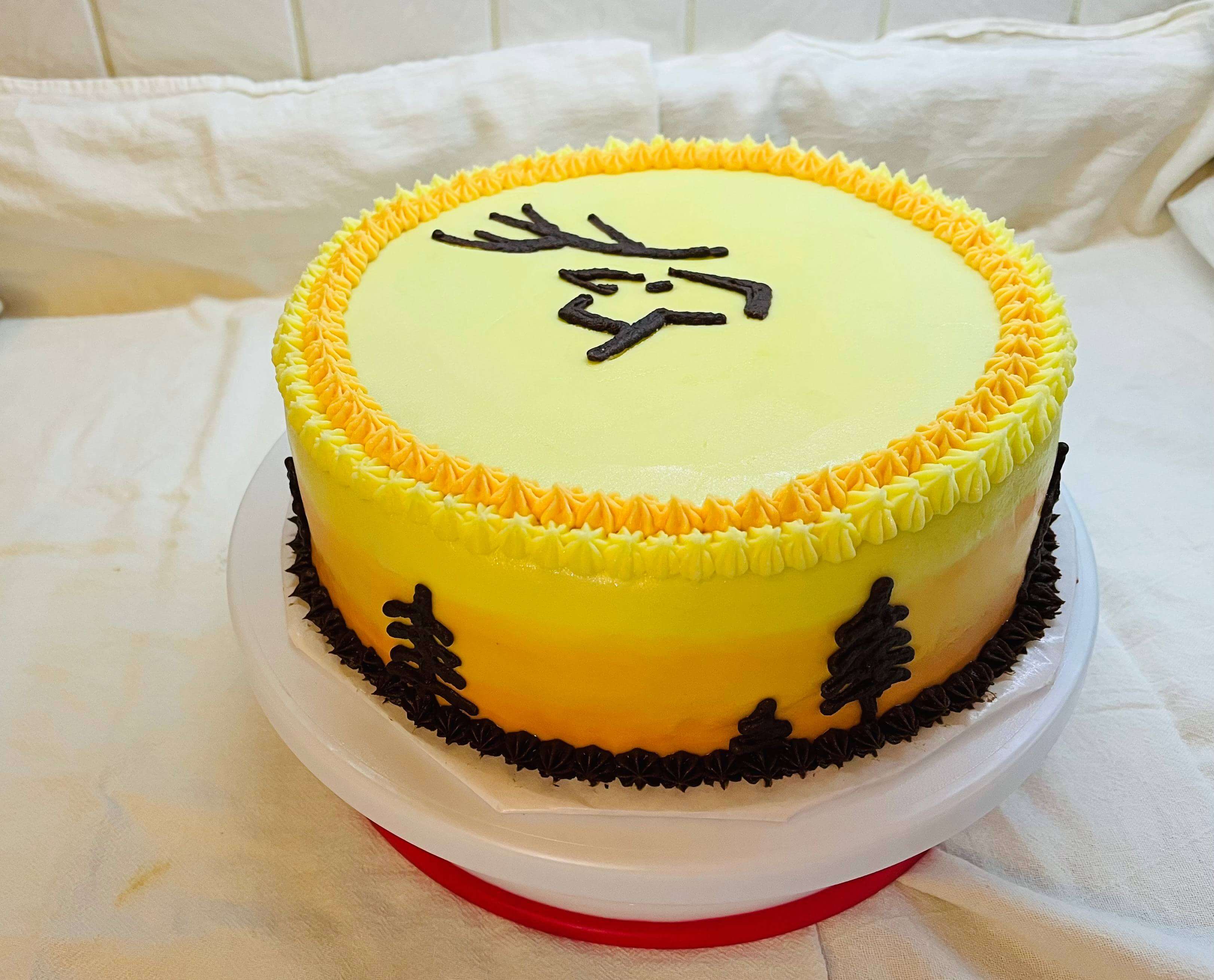 Decorated cake with as an early sunrise in the woods with a deer logo.