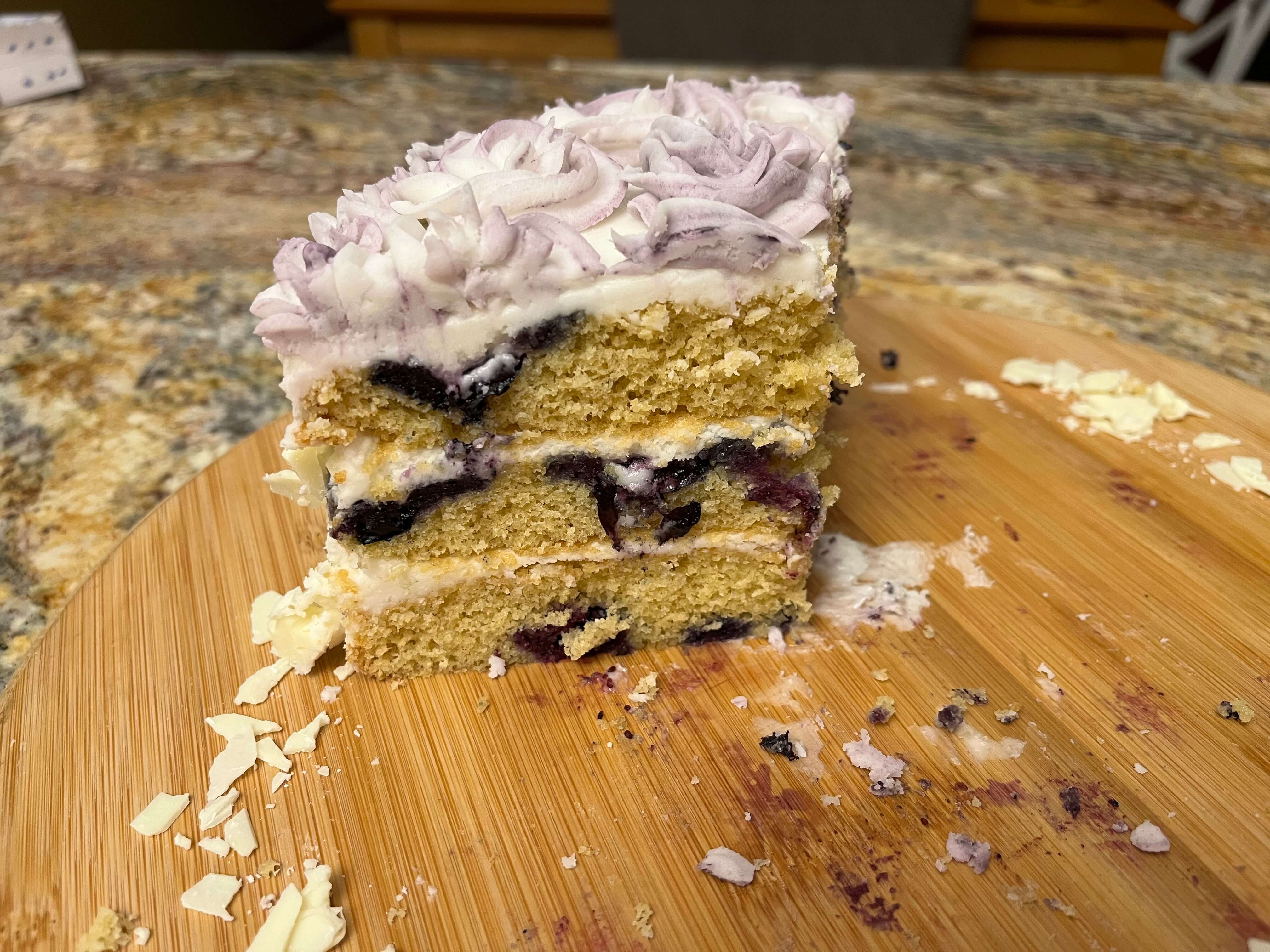 White chocolate and blueberry layer cake with white chocolate buttercream and white chocolate shavings.