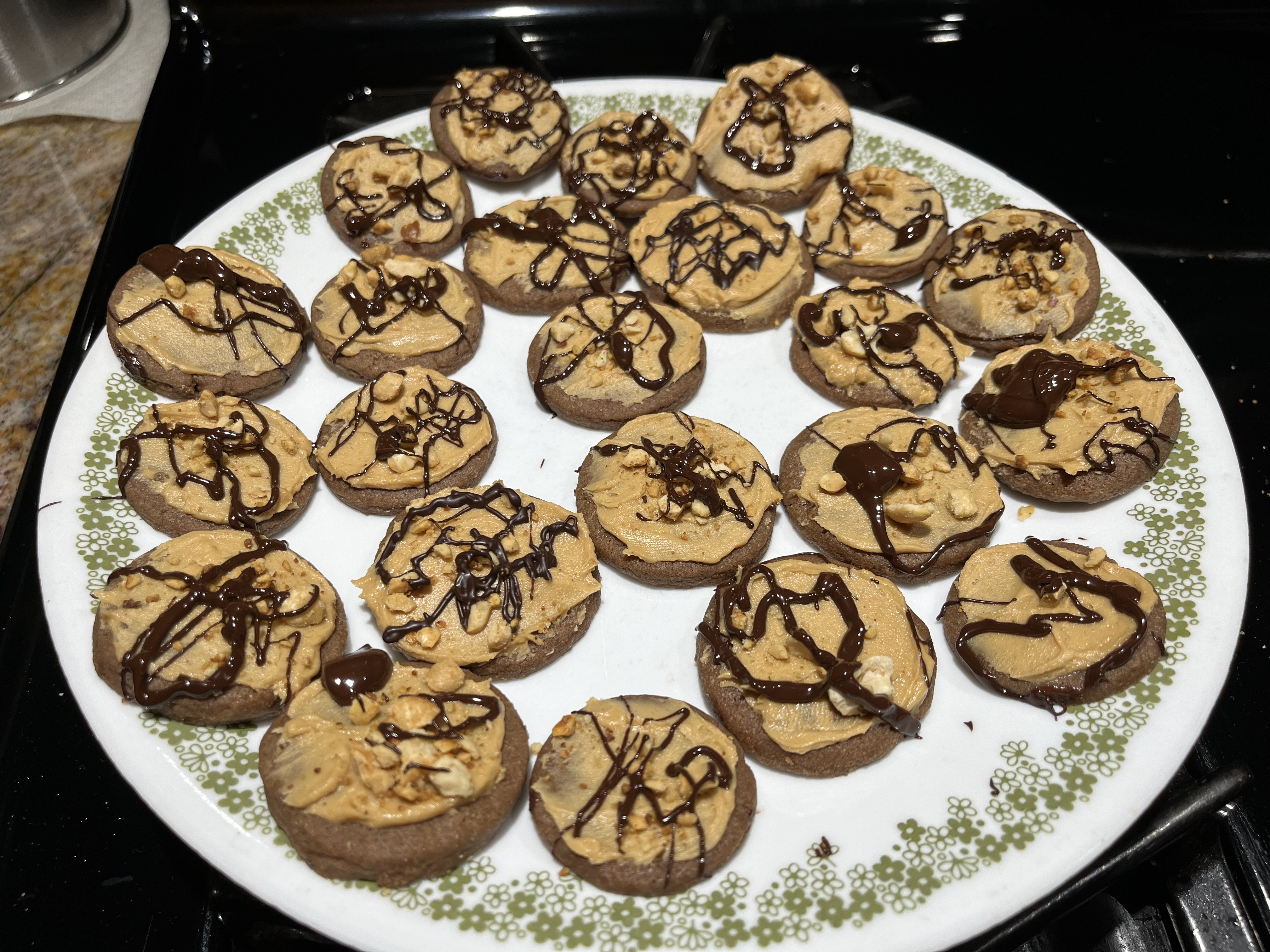 Chocolate cookie base with peanut butter frosting, topped with crushed peanuts and drizzled with dark chocolate.