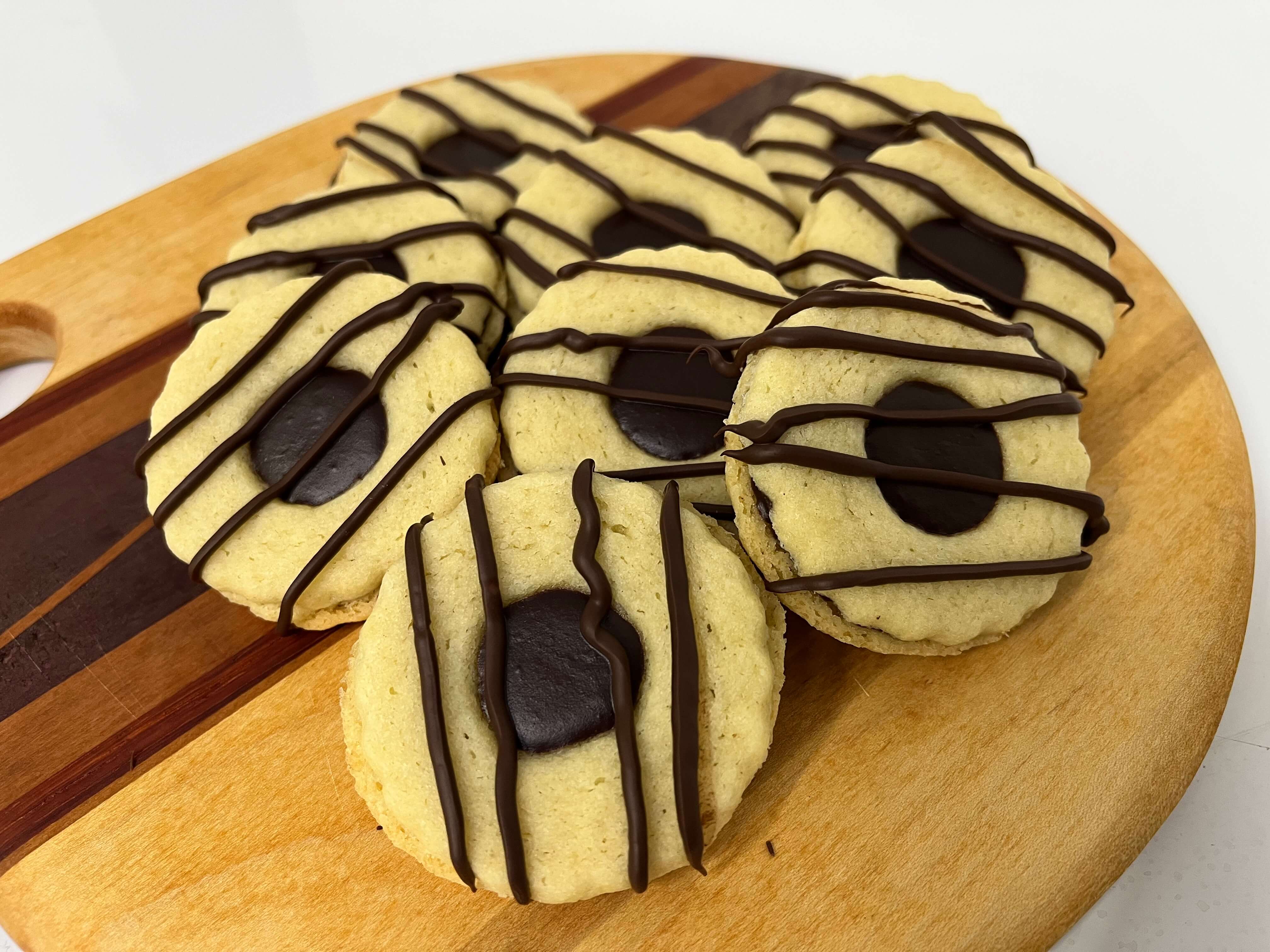 Two buttery cookies around a thick dark chocolate ganache center. With a generous drizzle of dark chocolate on top